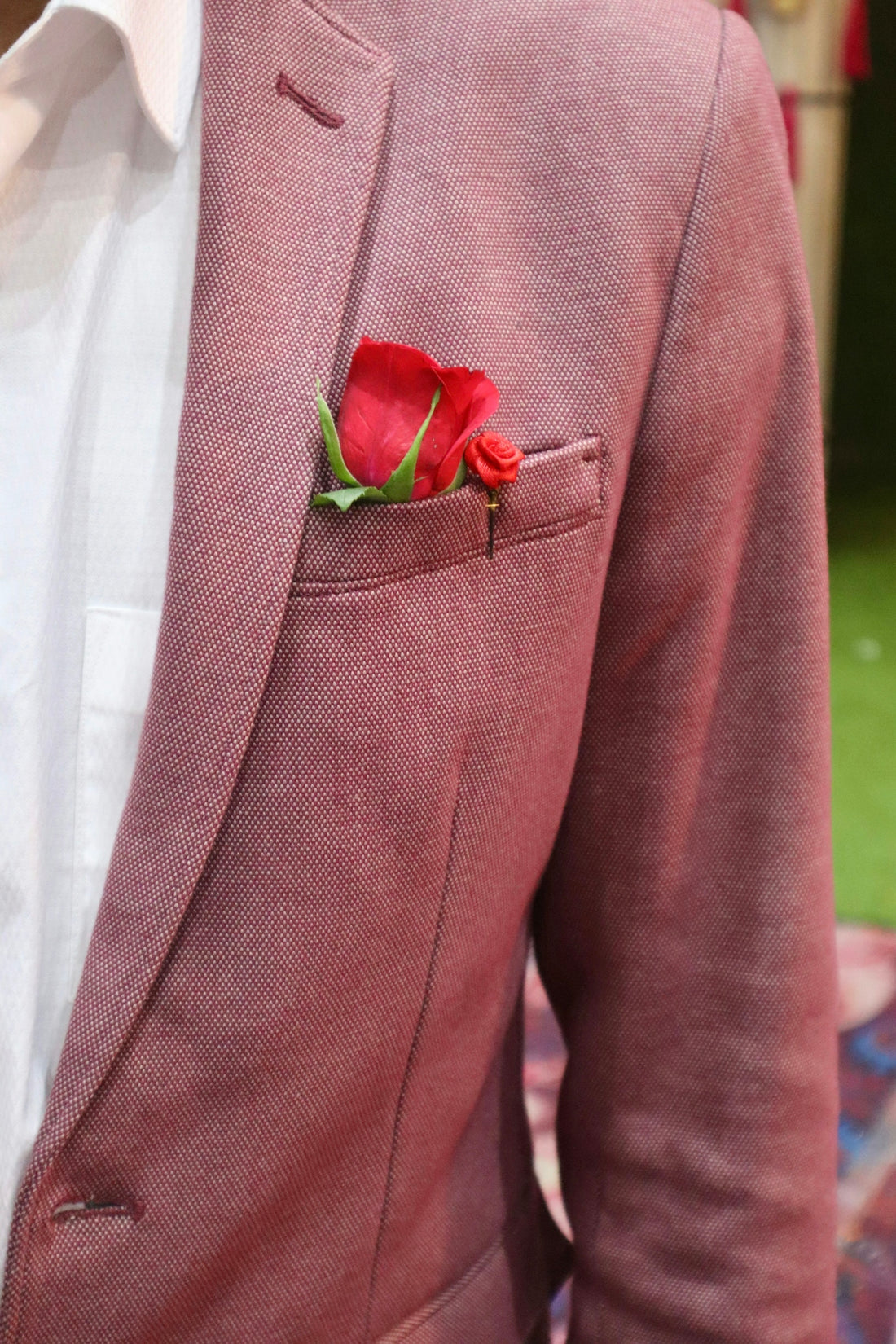 a man in a suit with a red rose in his pocket