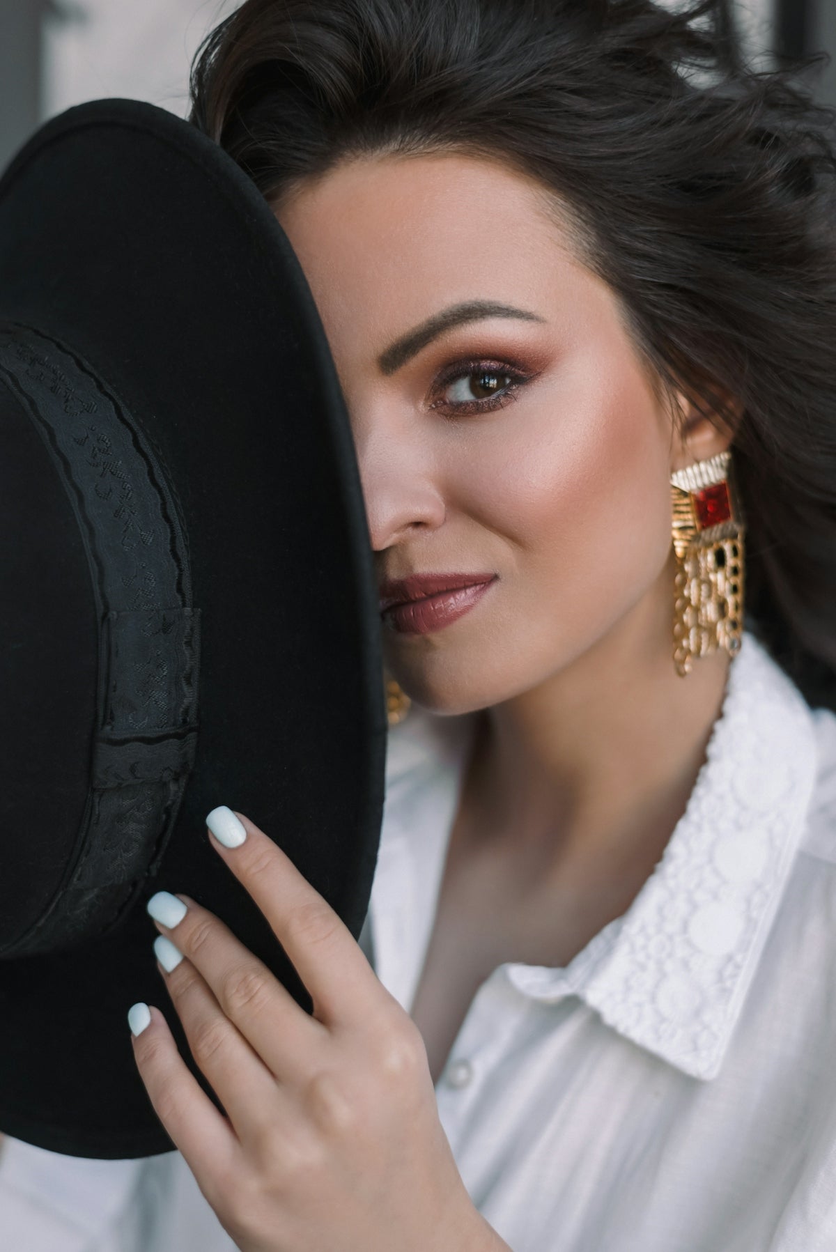 A woman in a white shirt holding a black hat