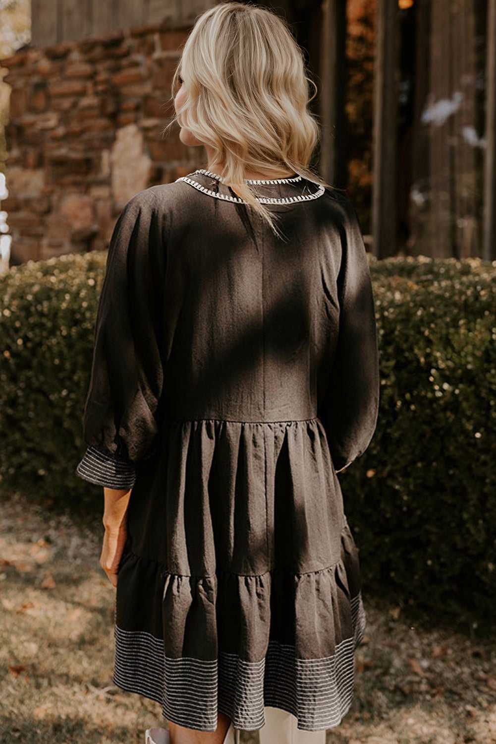 Back view of black Stitch Detail Tiered V‑Neck Babydoll Dress by FashionFitz®, highlighting tiered layers and textured hemline.