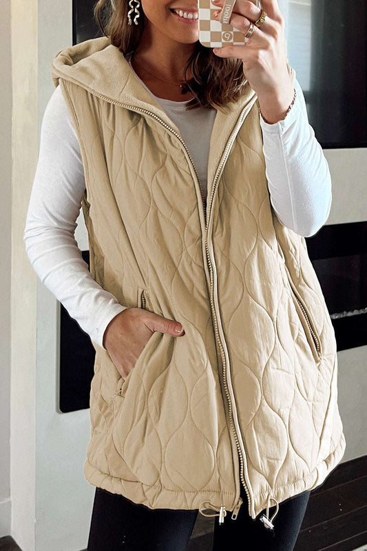 Women wearing khaki Quilted Fleece‑Lined Winter Gilet with front zipper and hood, styled over a white long-sleeve top and black leggings.