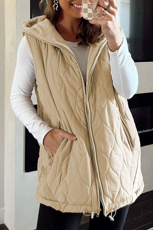 Women wearing khaki Quilted Fleece‑Lined Winter Gilet with front zipper and hood, styled over a white long-sleeve top and black leggings.