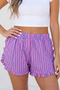 Person wearing pink and blue striped shorts with a white top on a light background