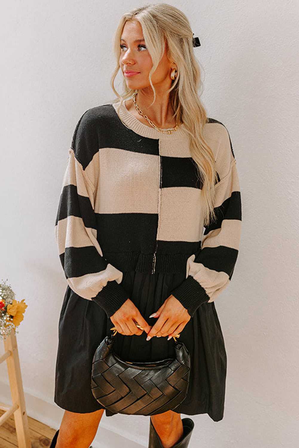Model holding a black handbag wearing Monochrome Knit Dress - Cozy & Stylish | FashionFitz with striped knit top and pleated skirt silhouette.