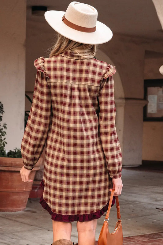 Person wearing a plaid dress and white hat with a brown band, standing outdoors.