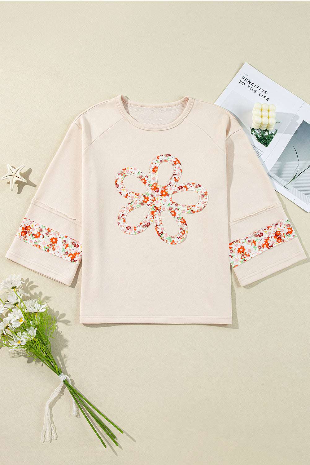 Flat lay of Beige Flower Graphic Top showcasing floral applique details on front and sleeves, ideal for casual spring wardrobe.
