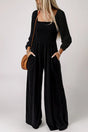 Woman wearing black smocked square neck wide leg jumpsuit with long sleeves front view Fashionfitz UK