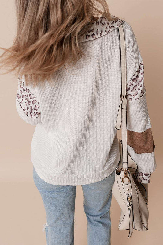 Embroidered Leopard Polo in white with leopard print collar and sleeves, textured fabric, and bow detail, styled with light denim jeans.
