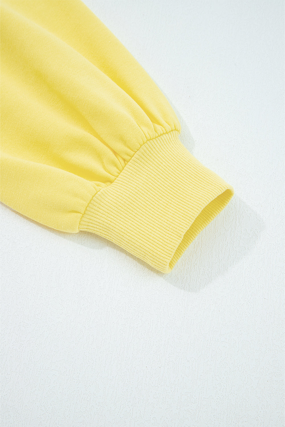 Close-up of yellow Drop Crop Set sleeve cuff with ribbed finish, emphasizing casual style and snug fit.