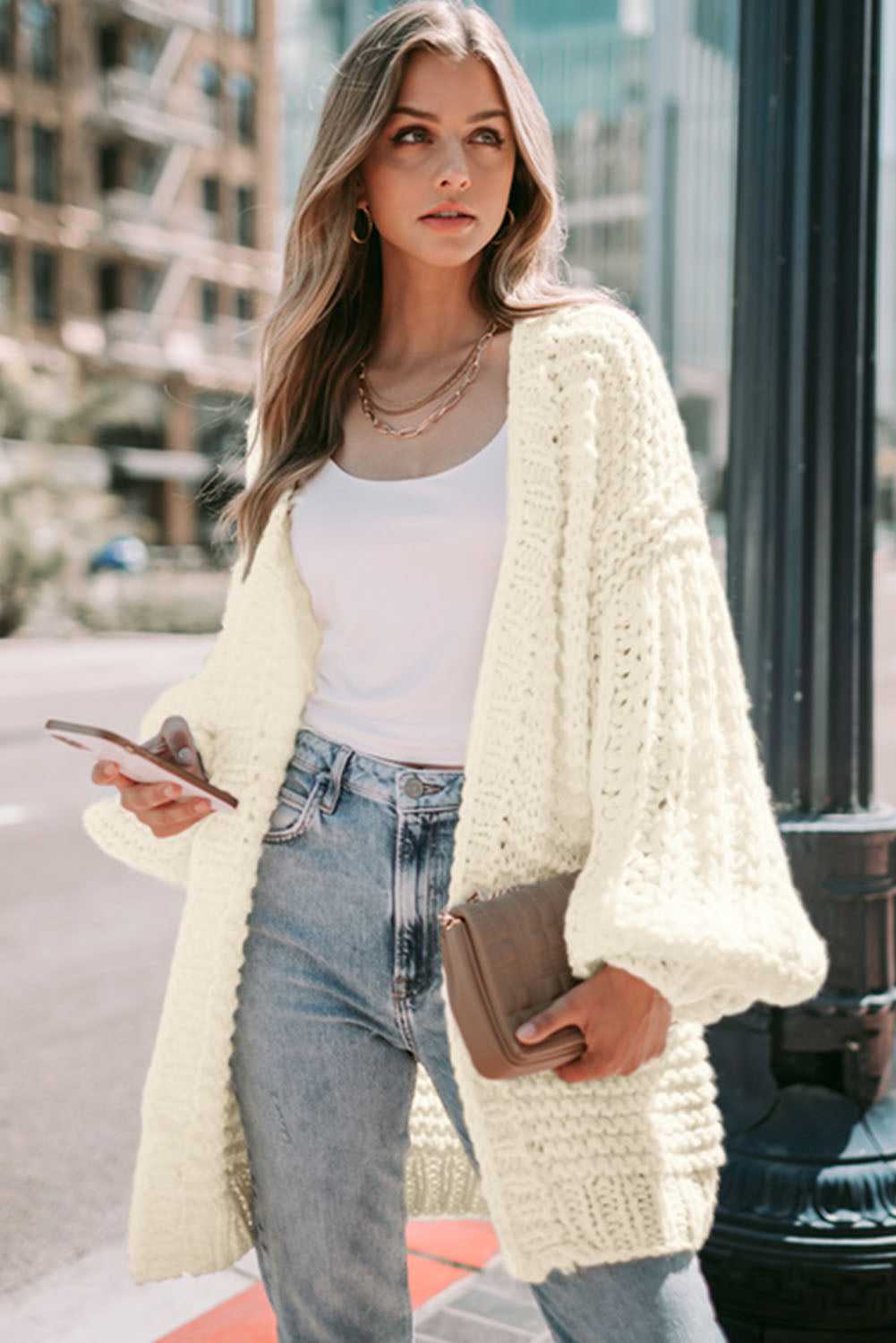 Chunky knit oversized white cardigan layered over casual outfit, ideal for autumn fashion and daily wear.