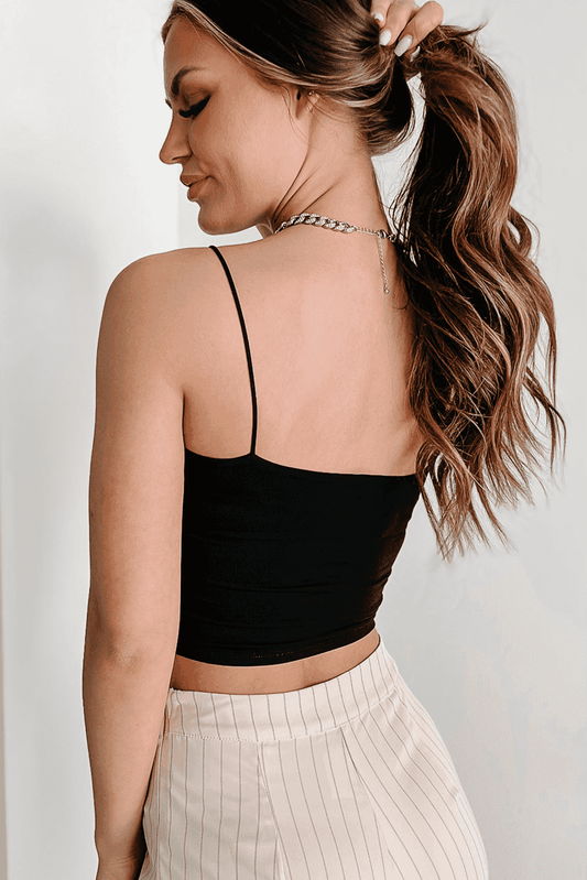 Back view of black spaghetti strap skinny fit crop top showing minimalist design and snug fit, paired with high-waisted pants.