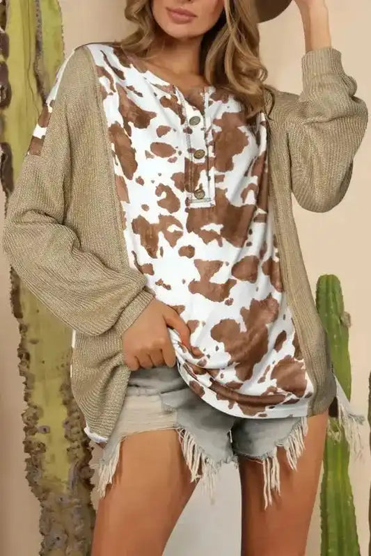 Animal Print Textured Henley Blouse with brown and white cow print front, ribbed knit sleeves, and button neckline, styled with denim shorts.