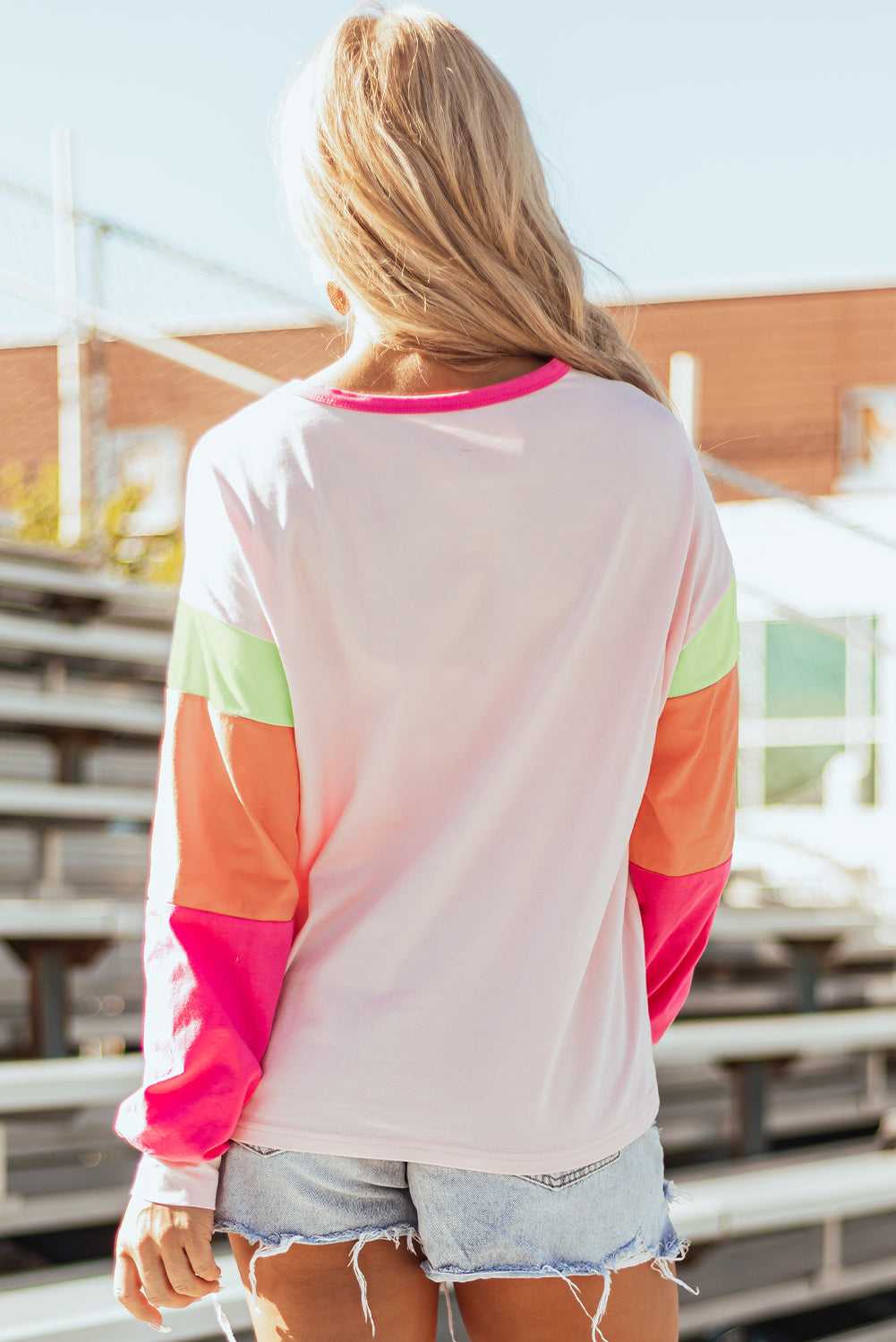 Back view of Pink GAME DAY Graphic Top showing solid light pink fabric and bold color block sleeves in green, orange, and pink.