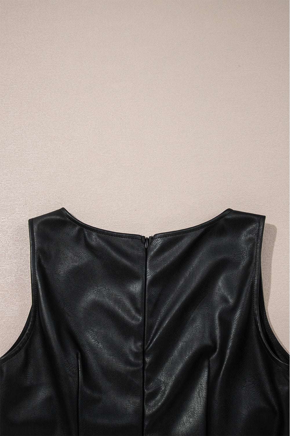 Detailed view of back zipper on Black Vegan Leather Sleeveless Mini Dress, designed for easy wear and seamless style by FashionFitz.