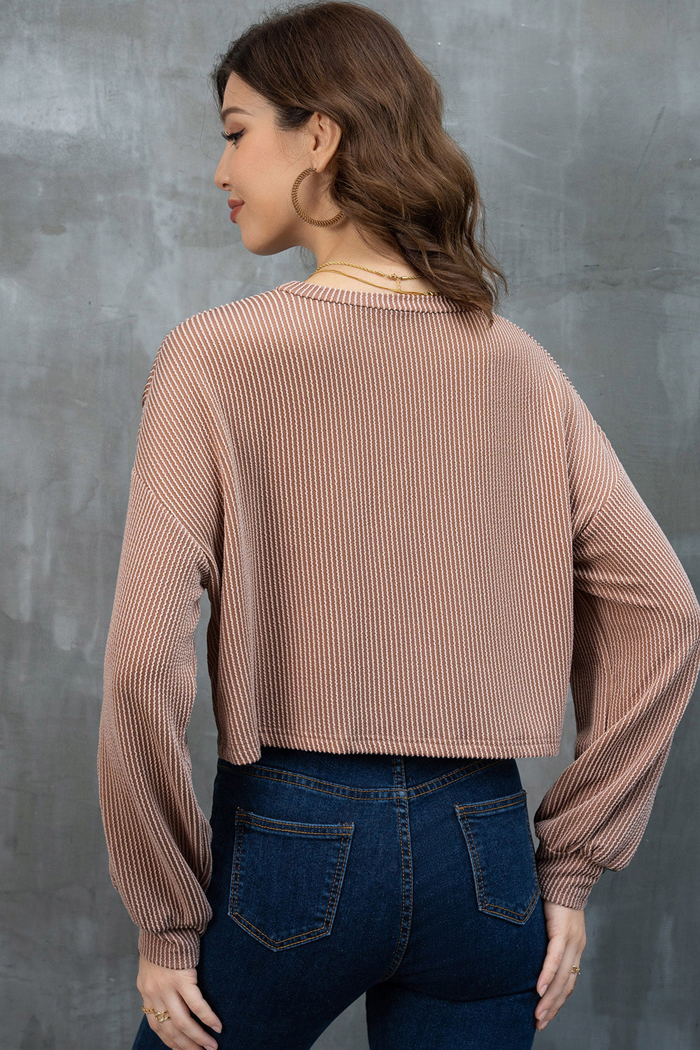 Woman wearing a Game Day Graphic Crop Top and blue jeans against a gray background