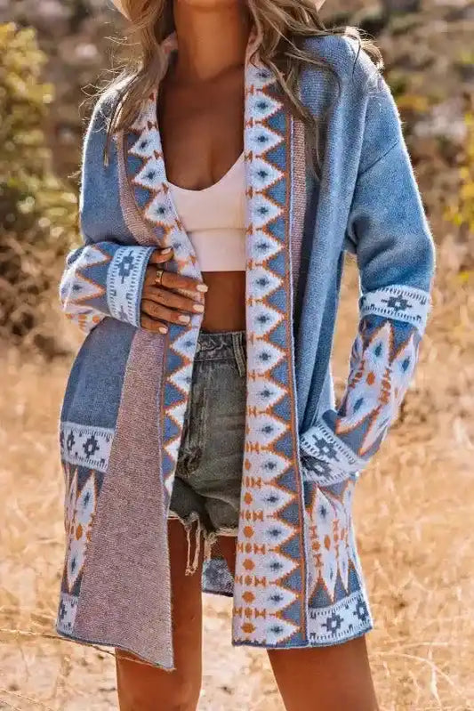 Blue Aztec Knit Duster Cardigan styled with white crop top and denim shorts, featuring bold Aztec patterns and open front design.