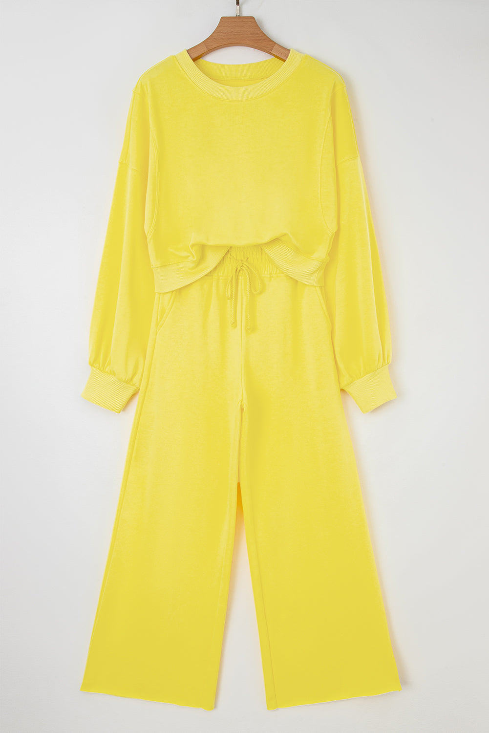 Flat lay of yellow Drop Crop Wide-Leg Pants Set on hanger, featuring cropped sweatshirt and wide-leg pants for casual wear.