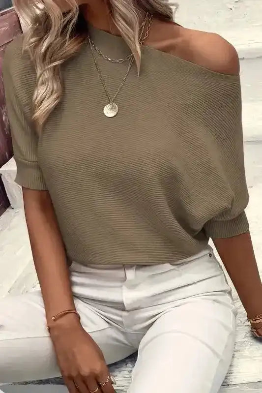 Coffee half sleeve knit jumper with ribbed texture styled off-shoulder, paired with white high-waisted pants for a chic casual look.