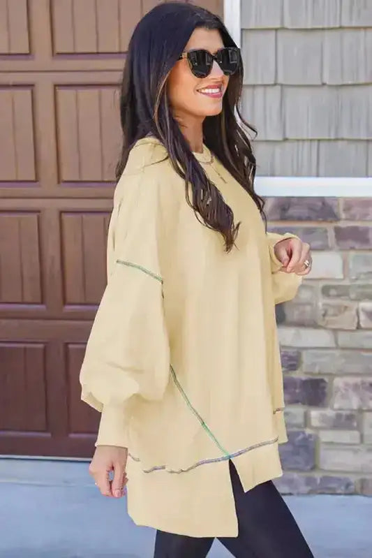 Side view of yellow oversized sweatshirt featuring colorful contrast stitching and split hem, ideal for relaxed streetwear looks.