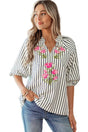 Woman wearing a striped shirt with floral embroidery by a poolside.