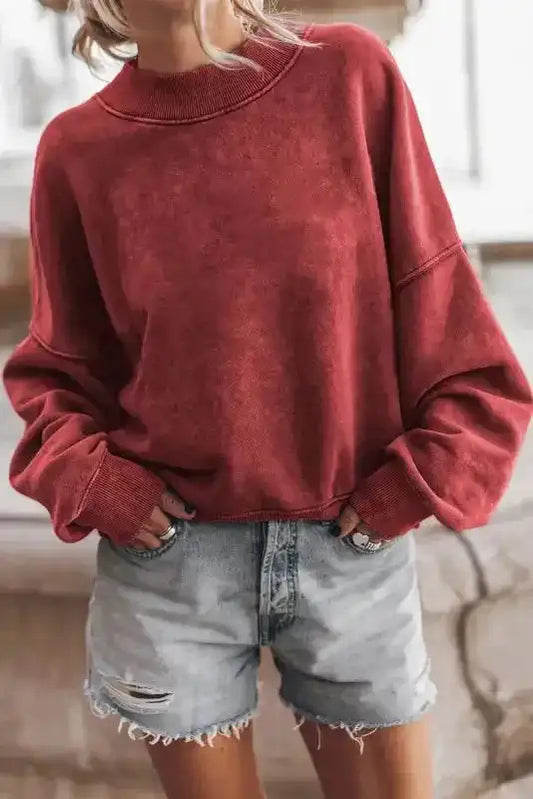 Cozy Drop Shoulder Crew Neck Sweatshirt in washed red styled with distressed denim shorts for a casual winter look.