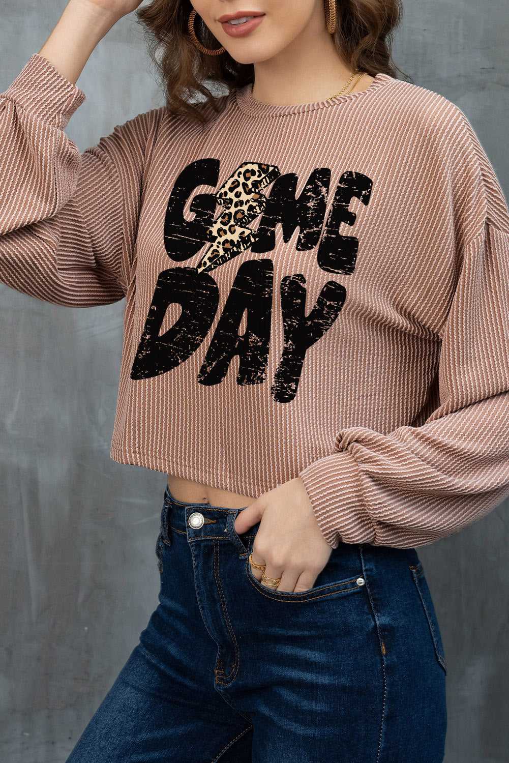 Person wearing a Game Day Graphic Crop Top, standing against a gray background.