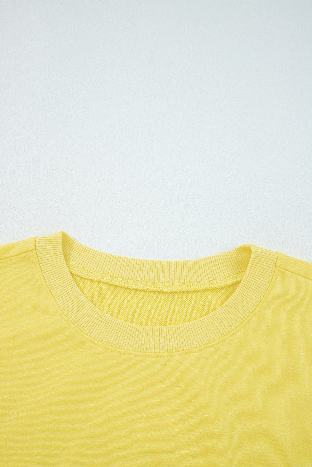 Close-up of yellow Drop Crop Set neckline with ribbed trim, highlighting quality construction and comfort-focused design.