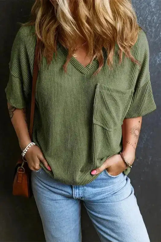 Women's corded V-neck loose T-shirt in olive green with chest pocket, styled casually with light blue jeans for a relaxed daily look.