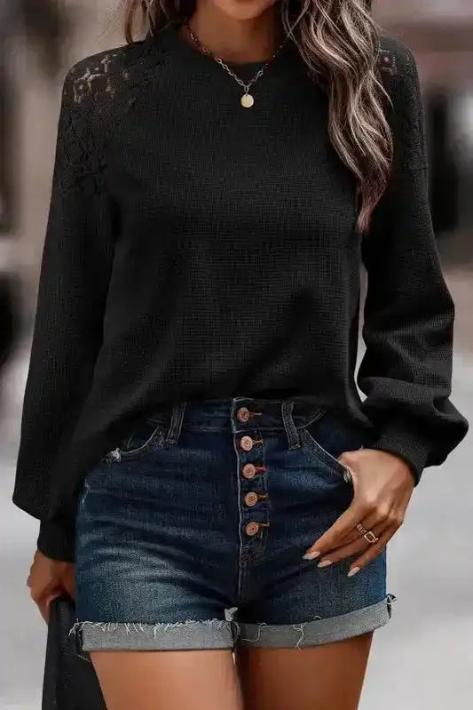 Black Lace Sleeve Textured Top styled with denim shorts, showcasing elegant lace shoulder detail and long sleeves for fall fashion.