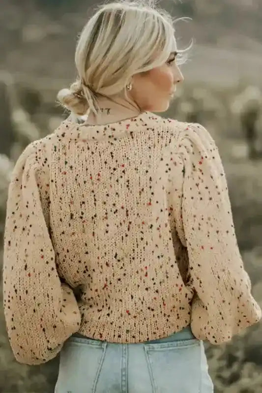 Back view of colorful cable knit sweater in beige, featuring textured knit and vibrant dot accents. Perfect for daily winter outfits.