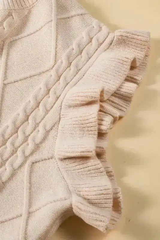 Detailed view of ruffled sleeve on oatmeal plus cable knit sweater, showcasing ribbed texture and feminine flutter design.