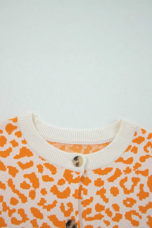 Orange chunky knit cardigan layered over neutral basics