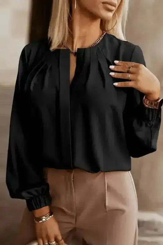 Black Pleated Neck Stretch Cuff Shirt for women styled with beige trousers. Elegant blouse ideal for work or casual outings.