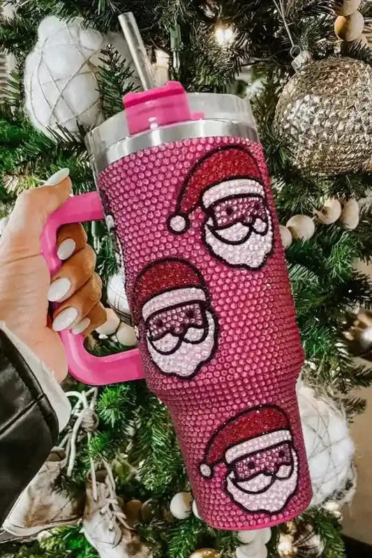 Santa Claus thermos cup with diamond rhinestones and pink handle, ideal for hot or cold drinks, shown in front of a Christmas tree.