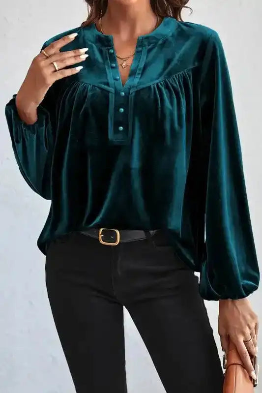 Skobeloff velvet blouse with beaded buttons and V-neck, styled with black jeans for an elegant winter look.