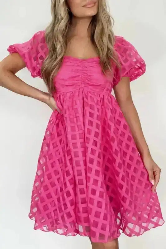 Ladies strawberry pink checkered babydoll dress with puff sleeves and ruched bodice, styled for summer events and casual outings.