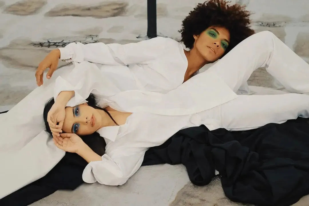 Two fashionable women in stylish white outfits posing gracefully on a textured surface