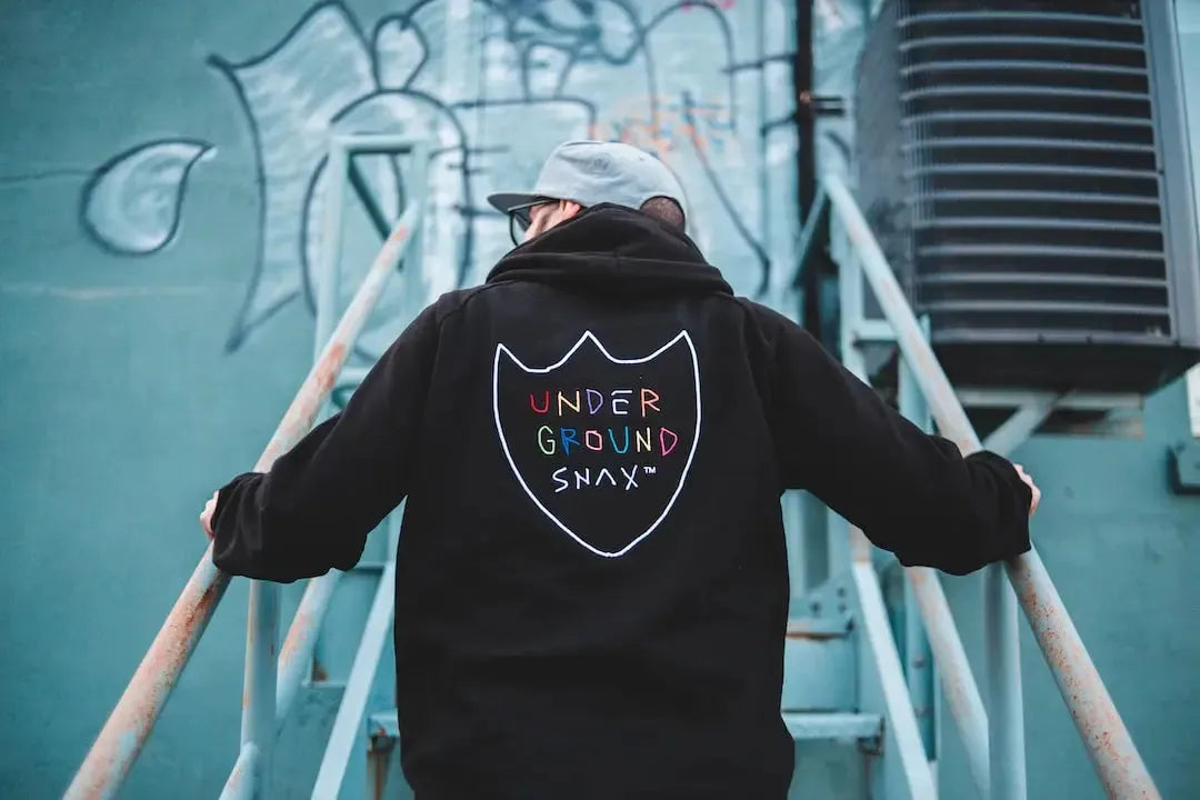 A person wearing a black hoodie with a colorful logo, showcasing streetwear style and urban fashion