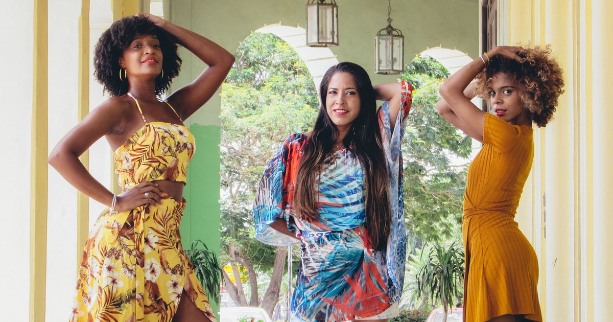 Three women in elegant floral dresses posing outdoors - UK garden party outfit 2026
