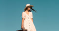 Woman in white dress holding leather suitcase on grass - old money aesthetic 2026