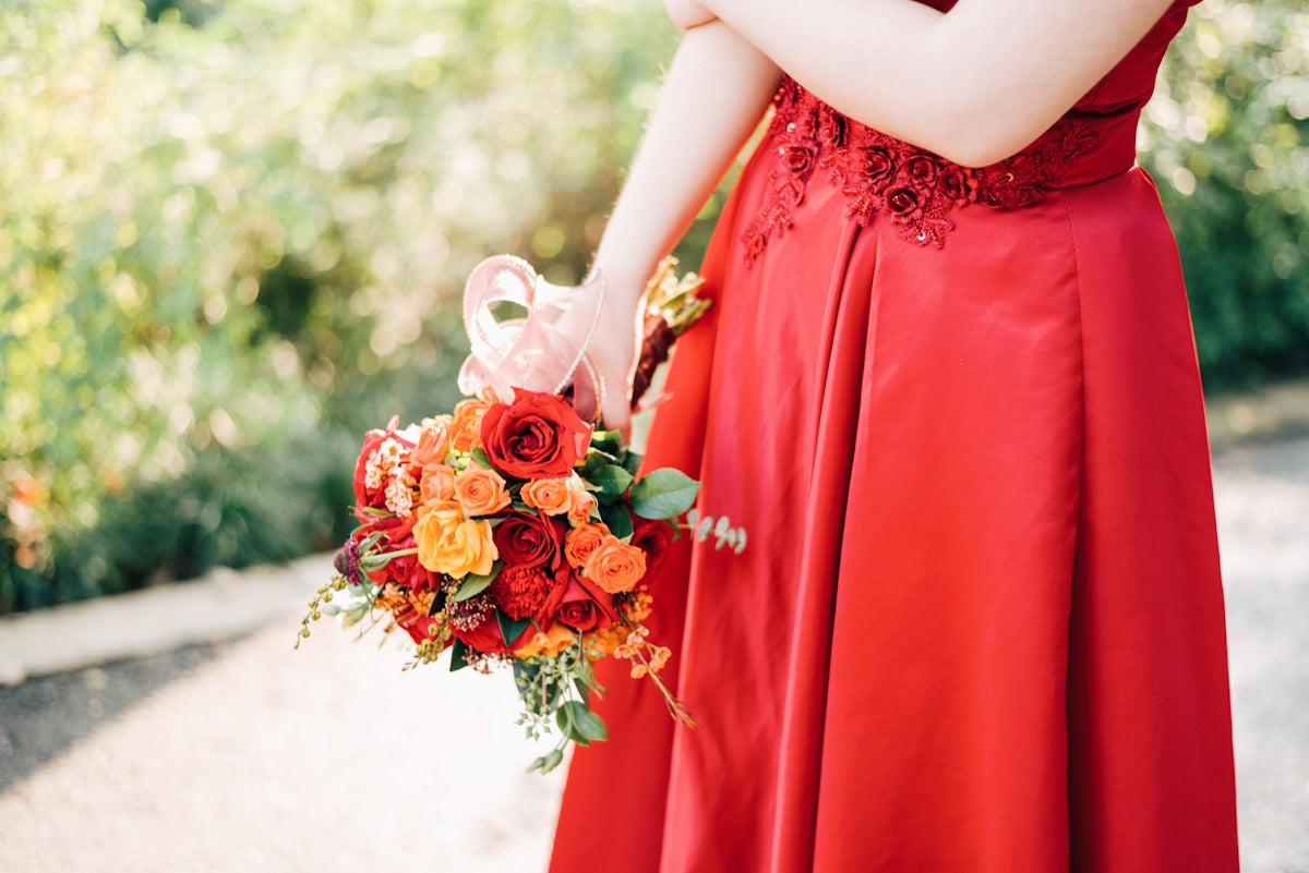 woman in red dress holding bouquet of red roses