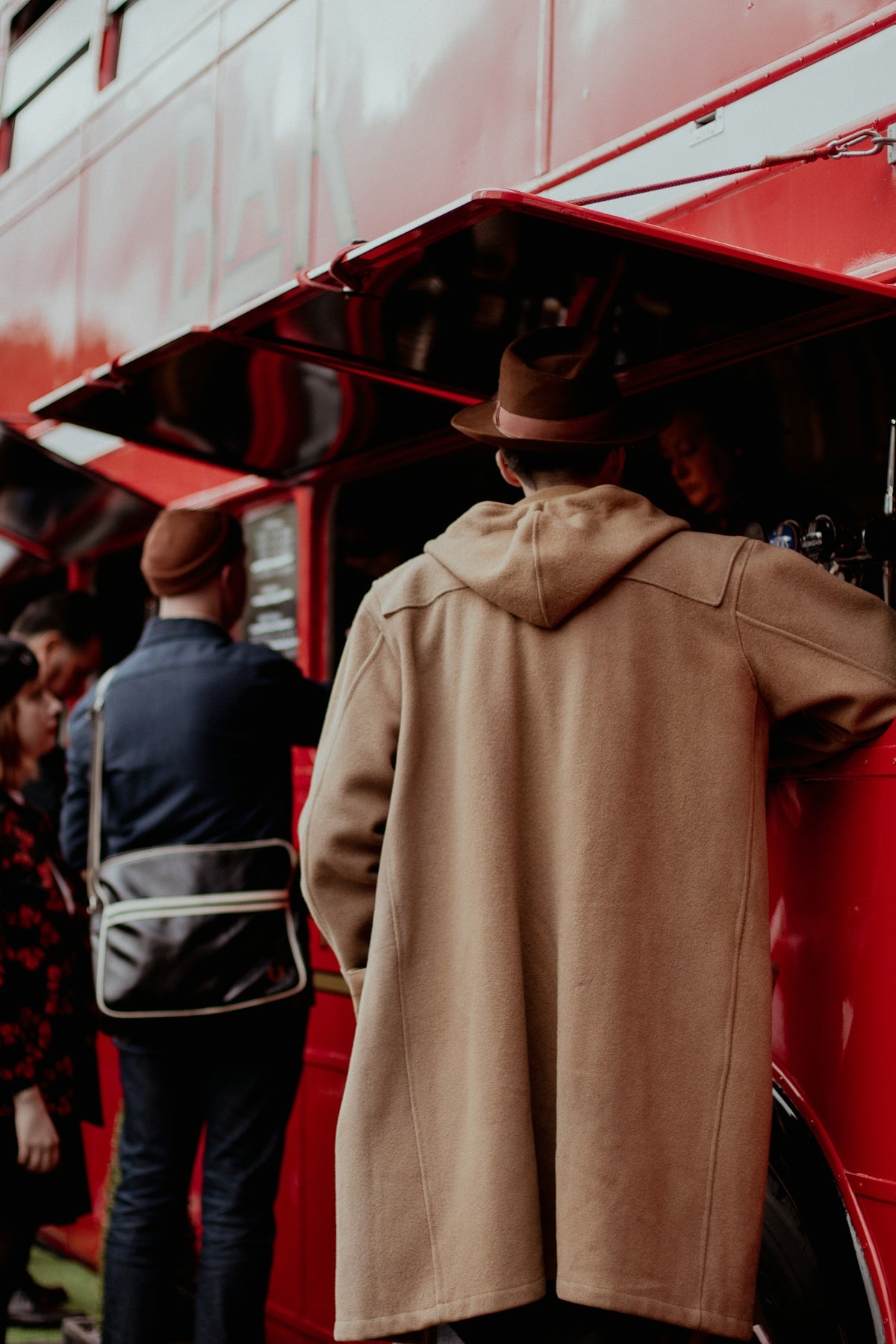 a group of people standing around a red double decker bus