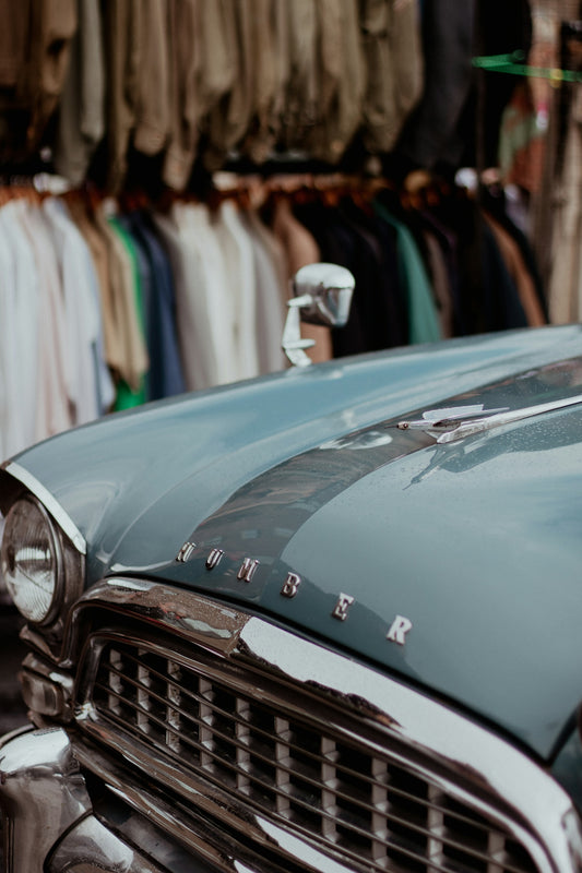 a car parked in front of a rack of shirts