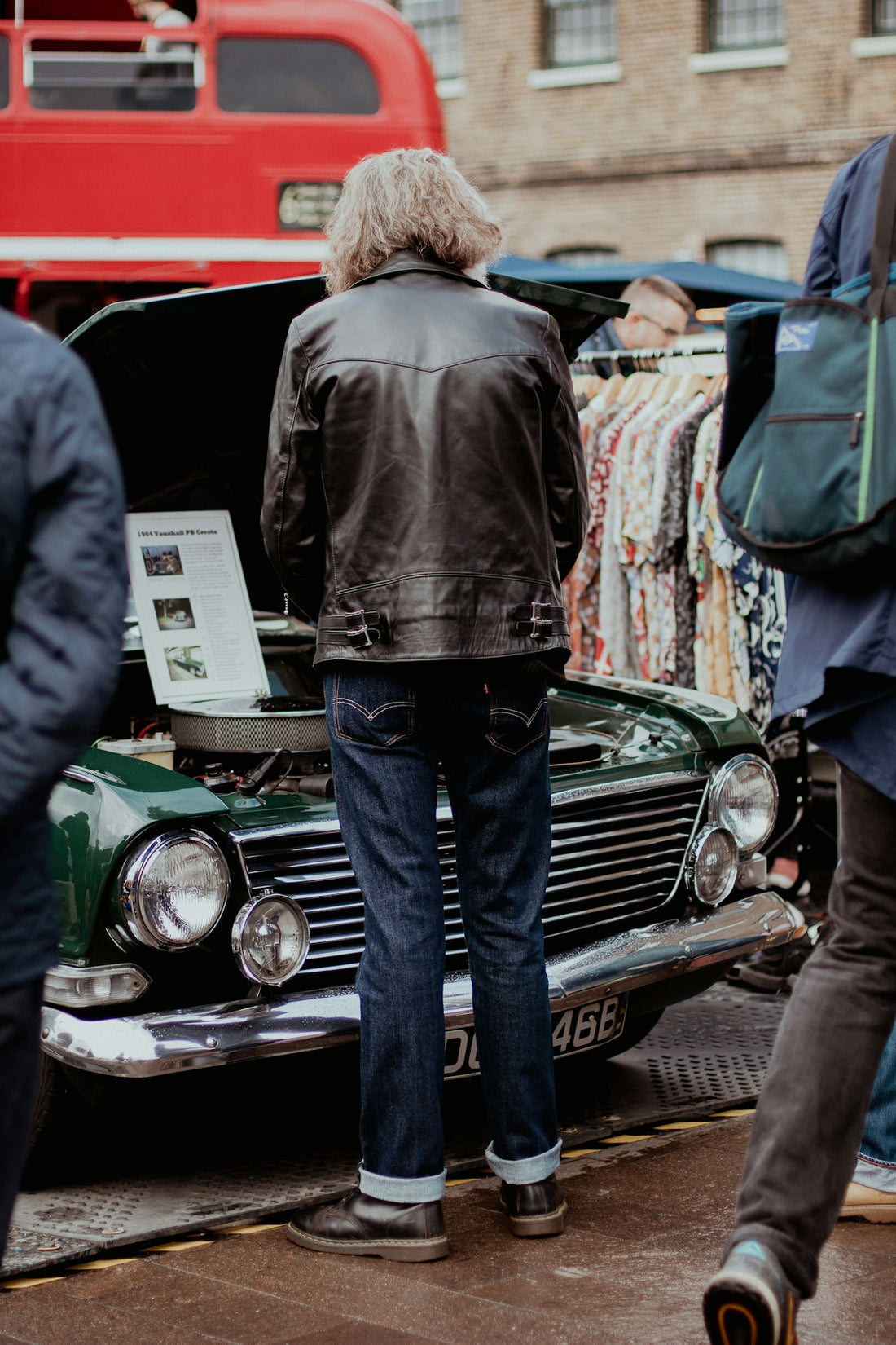 a group of people standing around a green car