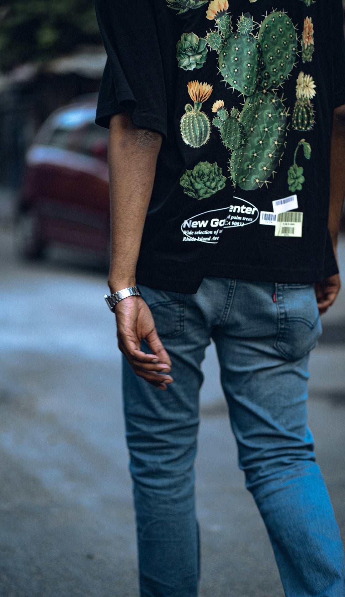 a man walking down a street with a cactus t - shirt on