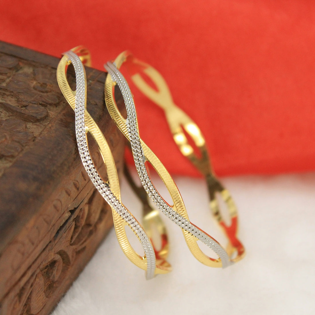 a pair of gold and silver bracelets sitting on top of a book