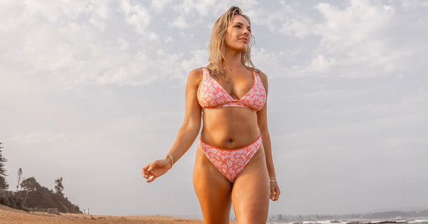 Woman in pink bikini walking on the beach - coastal cowgirl aesthetic 2026