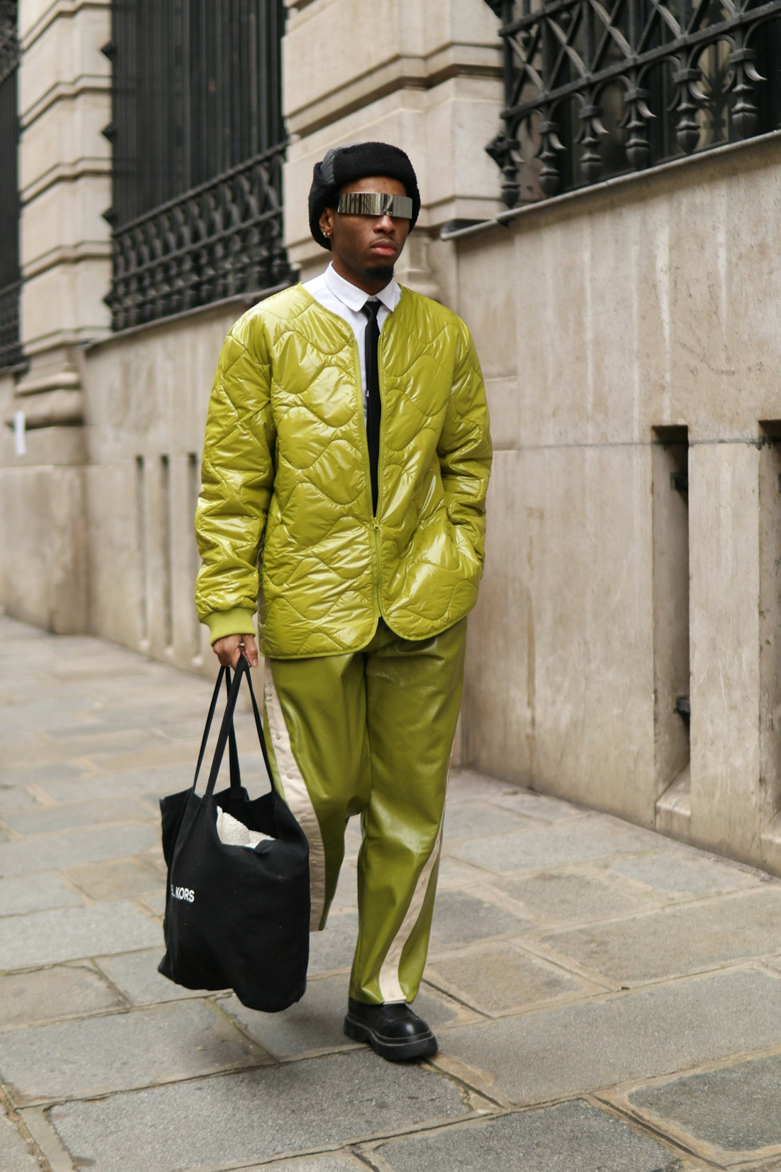A man in a yellow jacket and tie carrying a black bag