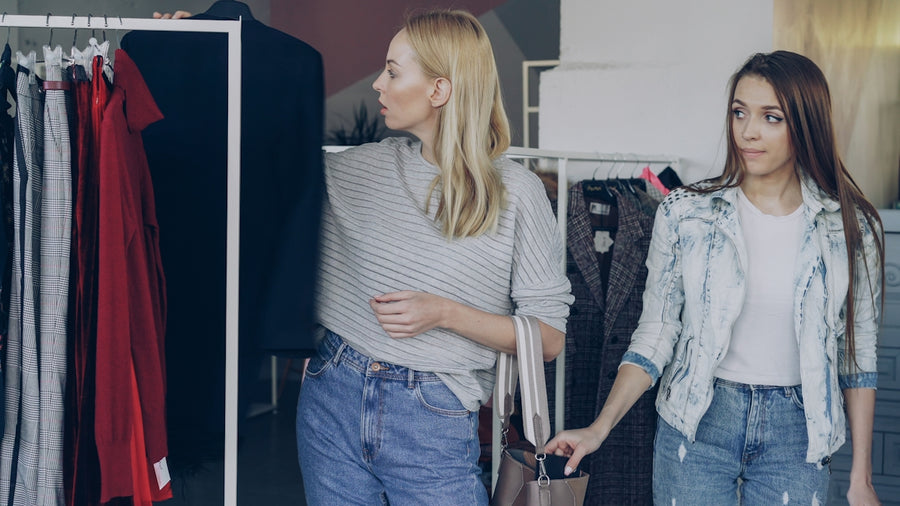 Two women are shopping for clothes in a store.
