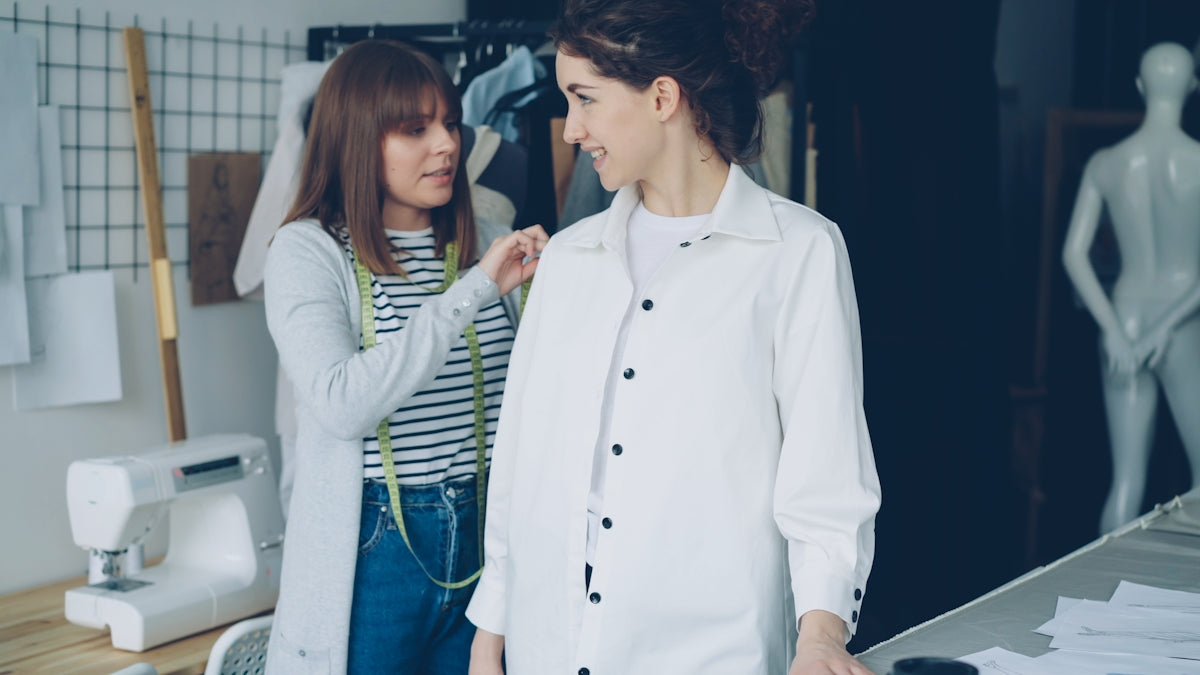 A seamstress measures a woman for a custom shirt.