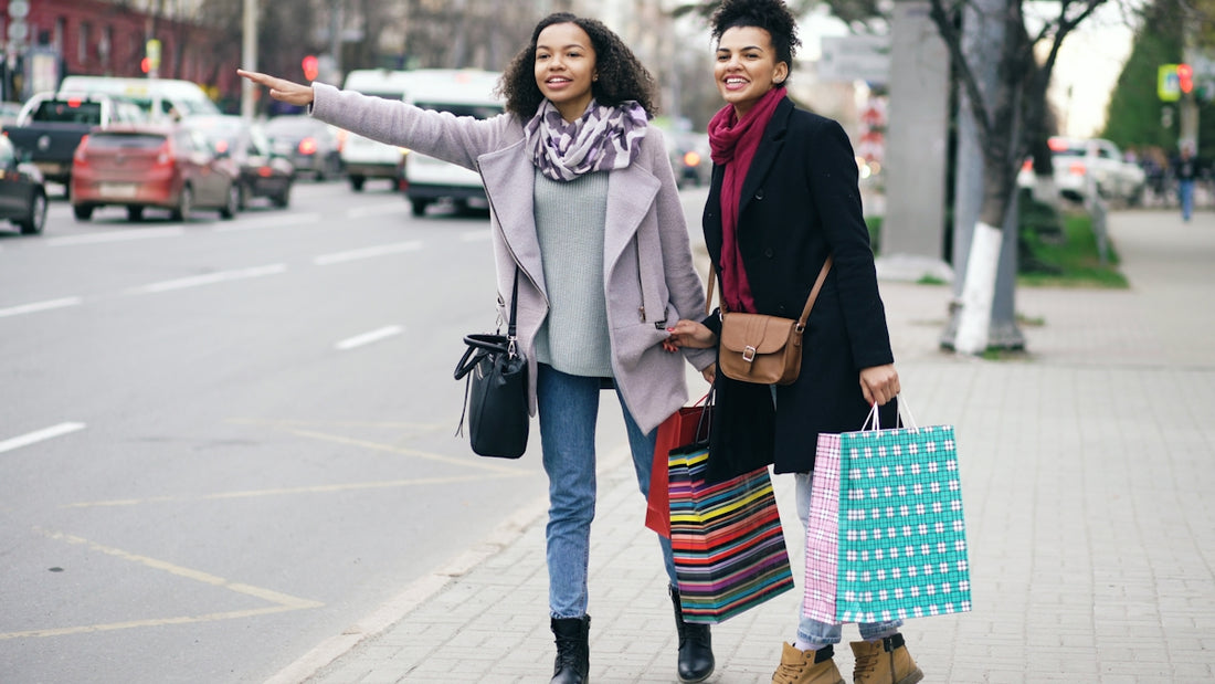 Two women hailing a taxi on a city street.